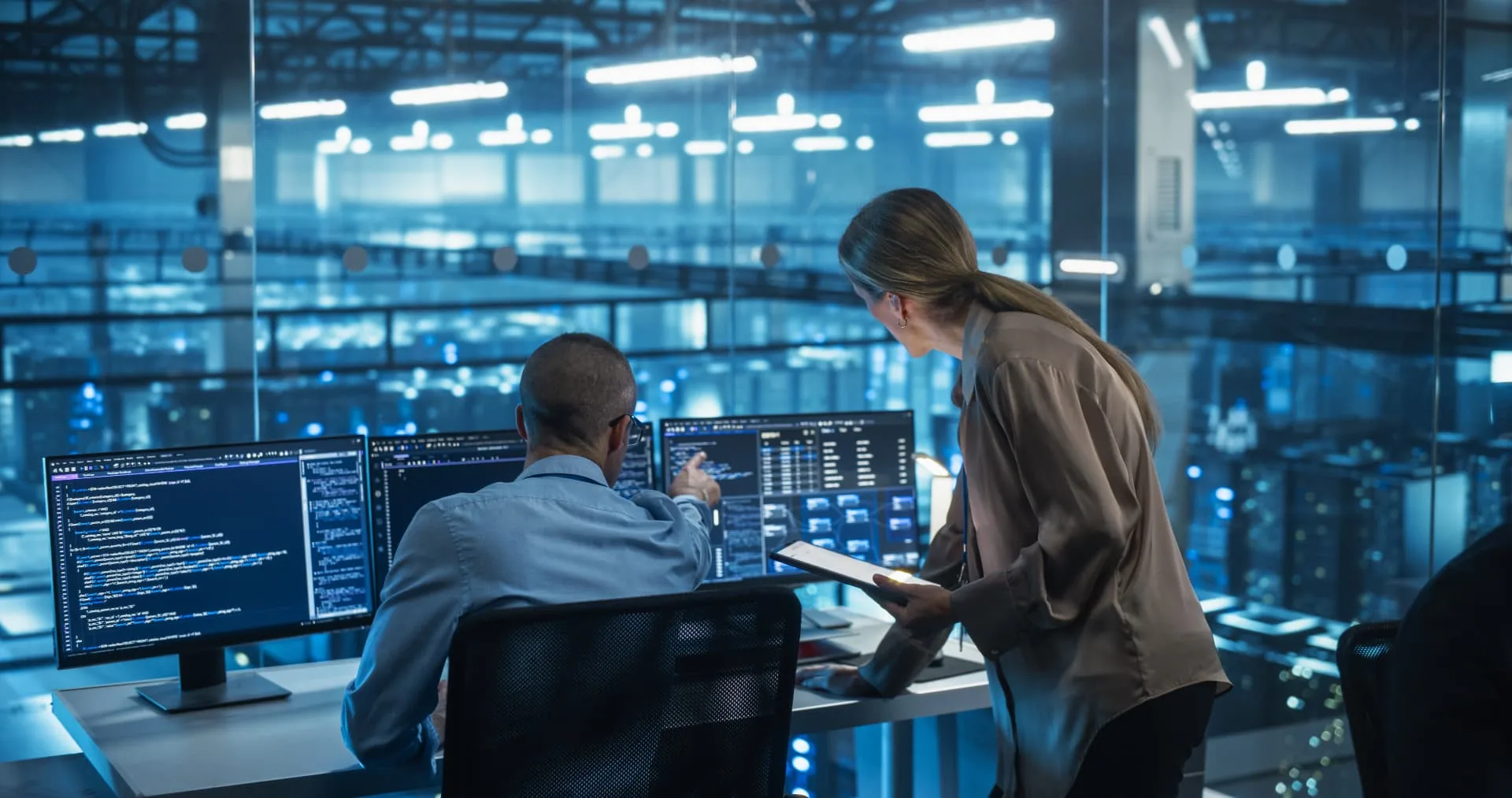 Two IT professionals reviewing systems on monitors inside an enterprise data-center operations room